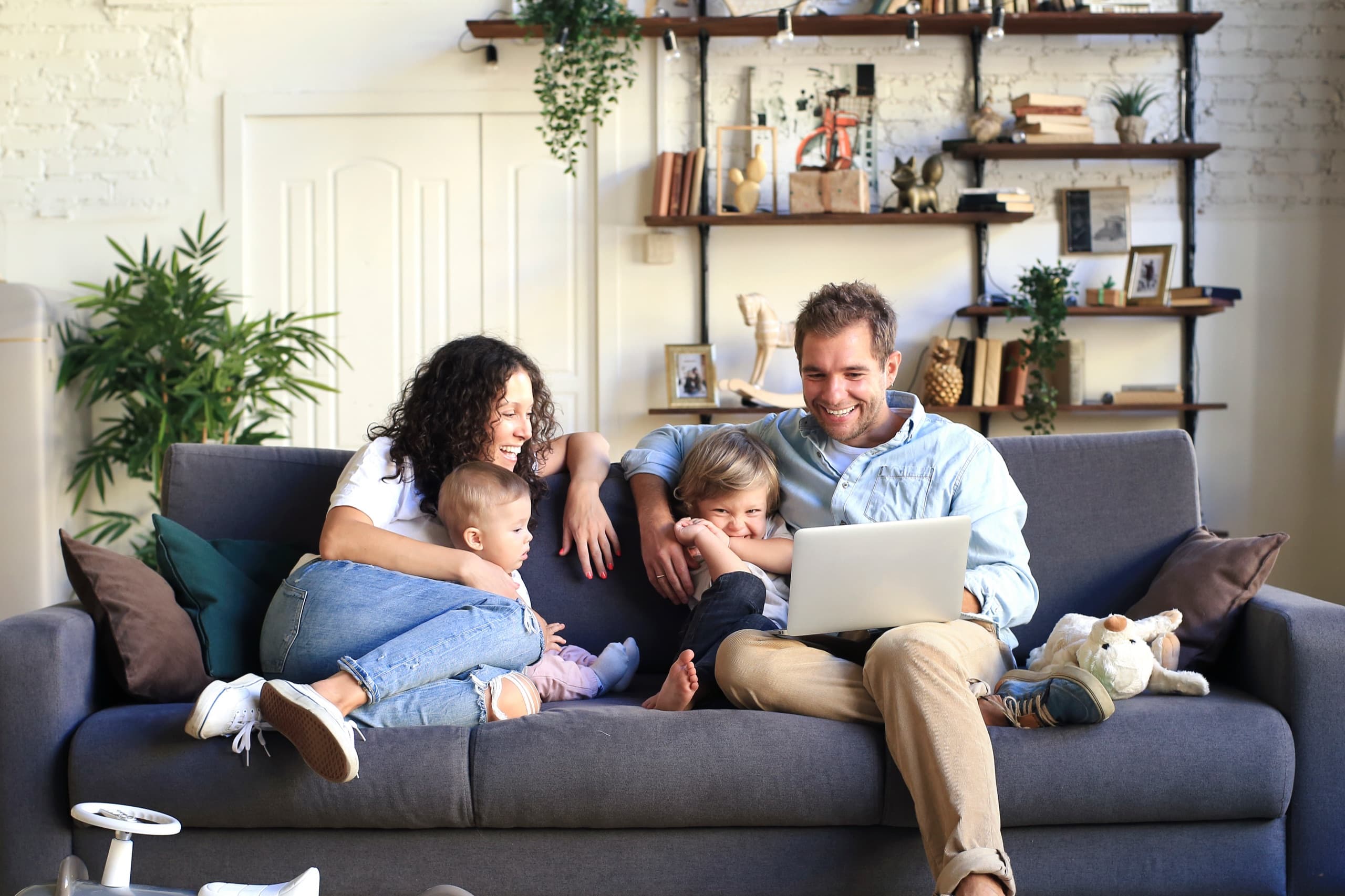 A family relaxing together on a sofa with a laptop