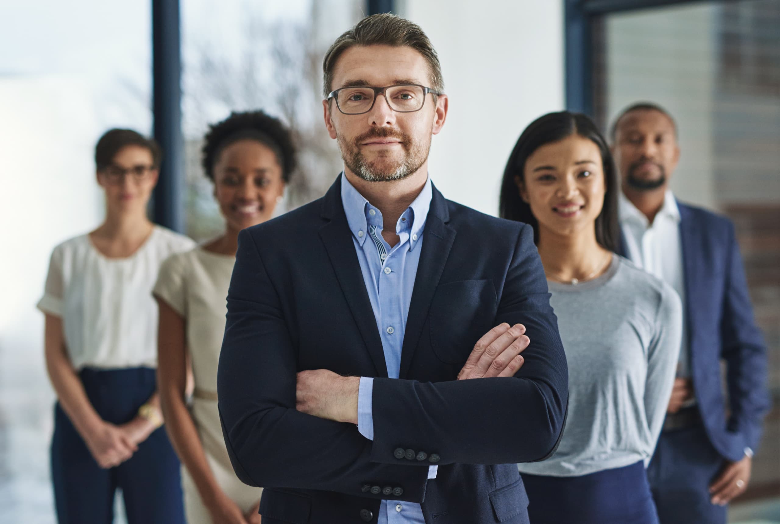 A business leader with crossed arms in front of his team